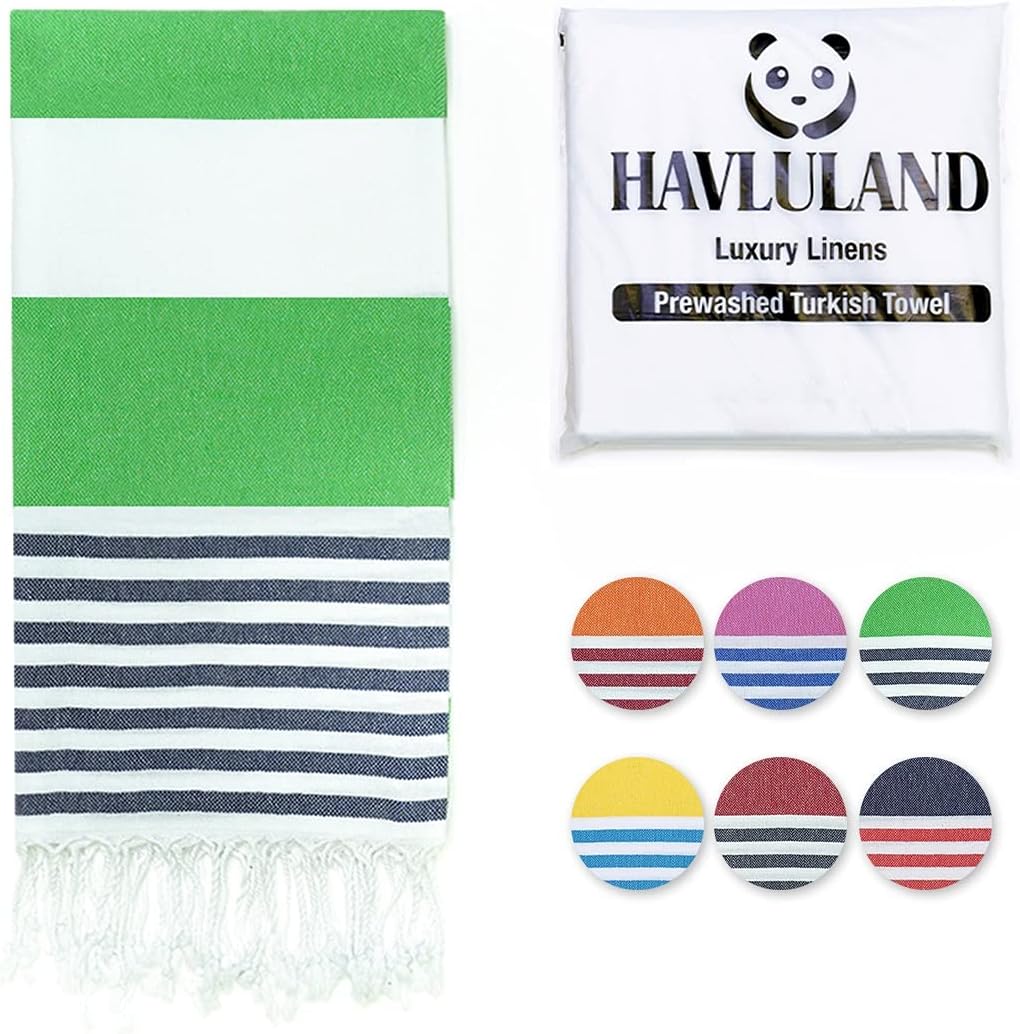 Havluland Turkish towel in green and white with navy stripes and fringe tassels, shown unfolded beside its white packaging. Six circular color swatch options are displayed in the lower right.